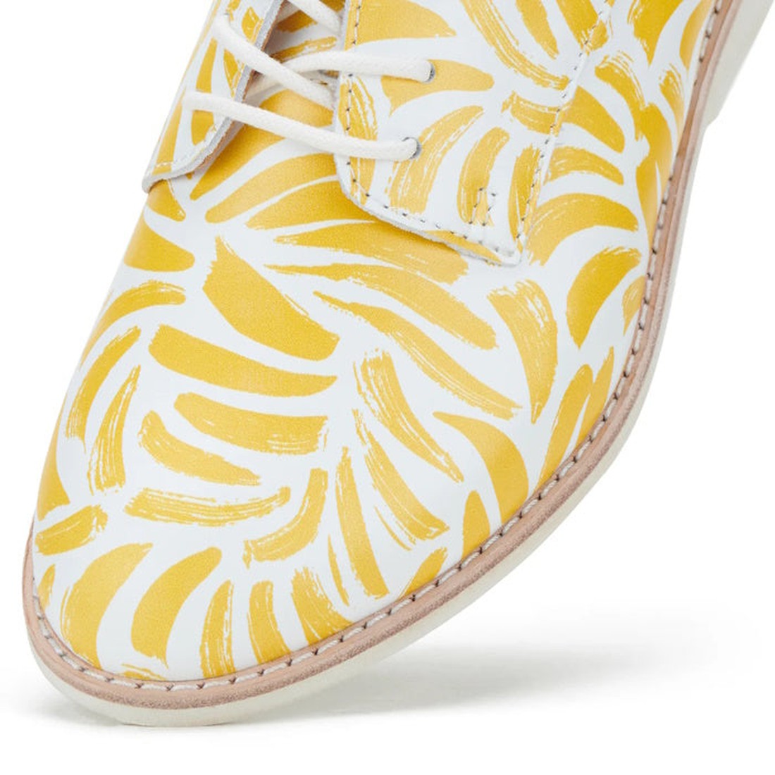Close-up of the Rollie Womens Derby Sunshine Splash Leather Shoe in white premium leather with yellow abstract brushstrokes, white laces, and light stitching along the sole for sneaker-like comfort., 9781760774783, 9781760774790, 9781760774806, 9781760774