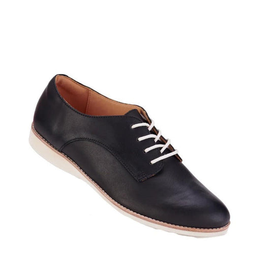 The Rollie Womens Derby Black Leather Brogue Shoe pairs premium black leather, white laces, and a light tan sole for classic style and sneaker-like comfort, displayed against a crisp white background.