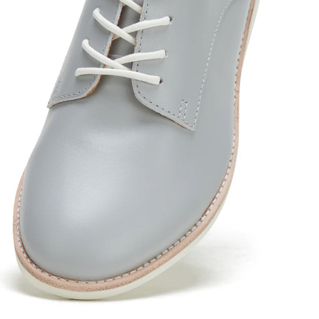 A close-up of the Rollie Womens Derby Super Soft Stone Leather Shoe in grey, featuring white laces and a light tan sole, highlights its sneaker-like comfort from the front and side against a white background., 9781760763930, 9781760763947, 9781760763954, 