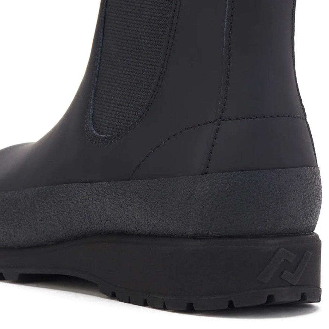 Close-up of the heel and side of the Rollie Womens Fields Chelsea Waterproof Rubberised Black Leather Boot, showing its textured rubber sole, stitched upper, elastic side panel for easy wear, and an embossed logo on the back of the sole., 9339554341965, 9