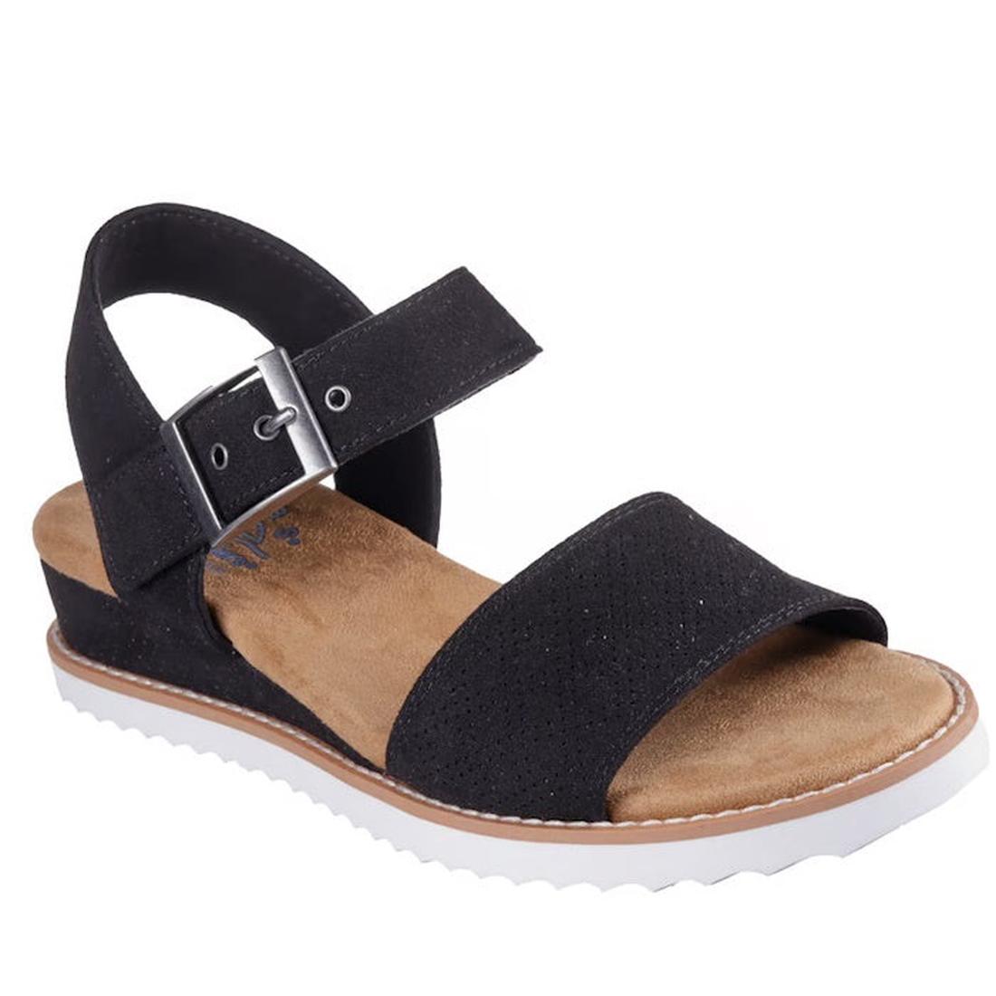 The Skechers Bobs Womens Desert Kiss Serendipitous Black WIDE Sandal features an open-toe design, thick front strap, silver-buckled ankle strap, cushioned tan Memory Foam footbed, wedge heel, and a white ridged sole.