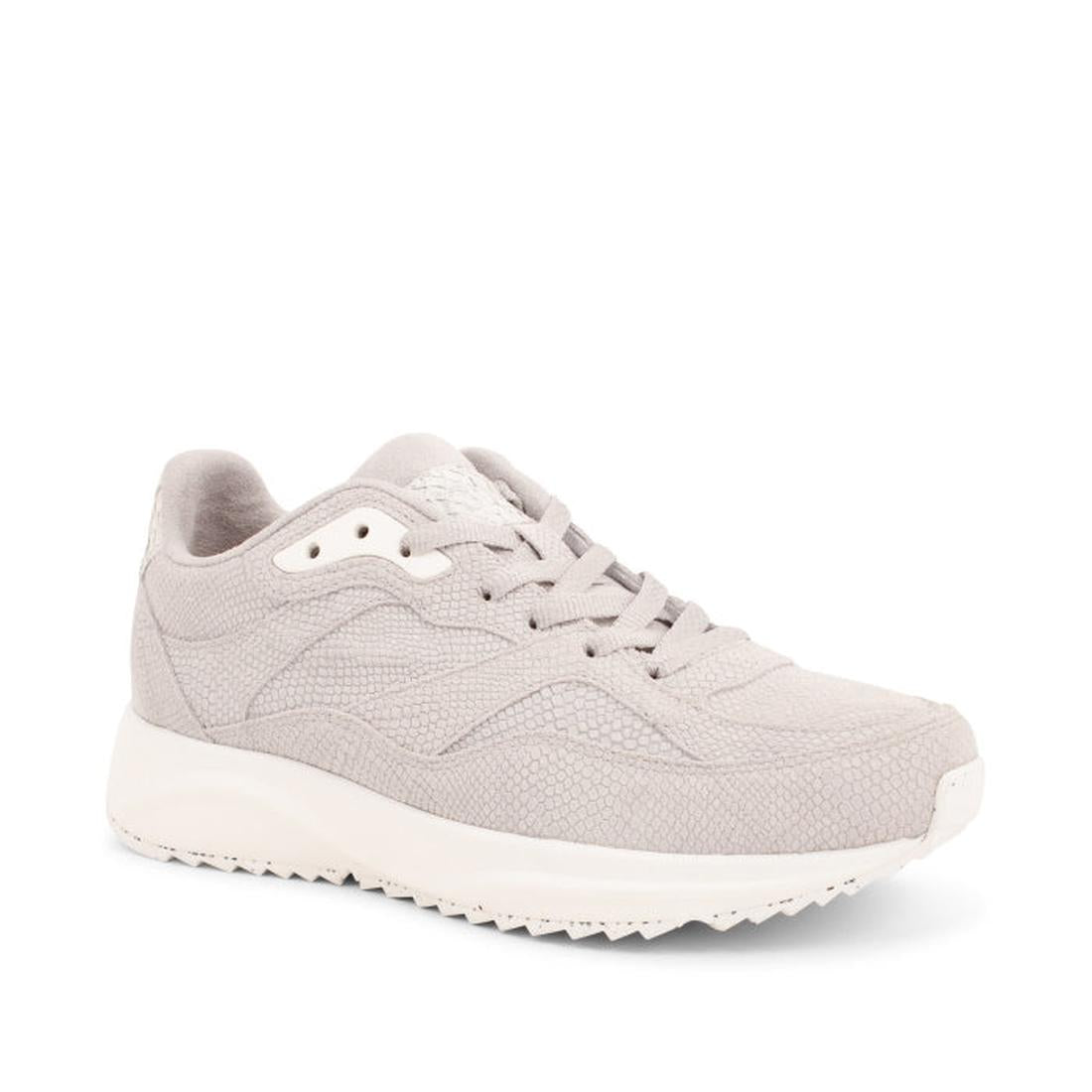 The Woden Sophie Snake Suede Sea Fog Grey Women's Sneaker features a light gray Scandinavian minimalist design with textured fabric, matching laces, and a white rubber sole as seen from the front angle.