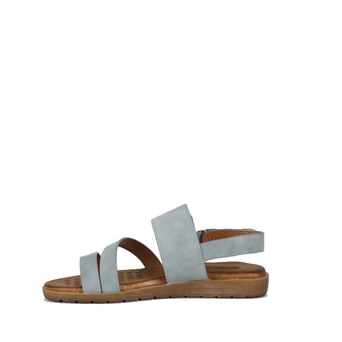 The Soultbush Flinders Denim Women’s Sandal with Back Strap features a light blue synthetic upper, two front straps, an ankle strap, and a flat brown sole with a cushioned footbed, shown in side profile on a white background.