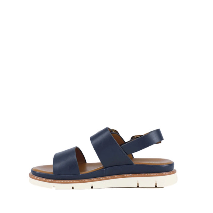 Introducing the Soultbush Garie Navy Blue Women’s Sandal with Back Strap: featuring two wide navy straps, a secure ankle strap with a buckle, a tan cushioned footbed, and a thick white sole with subtle grooves—perfect sandals for effortless coastal living