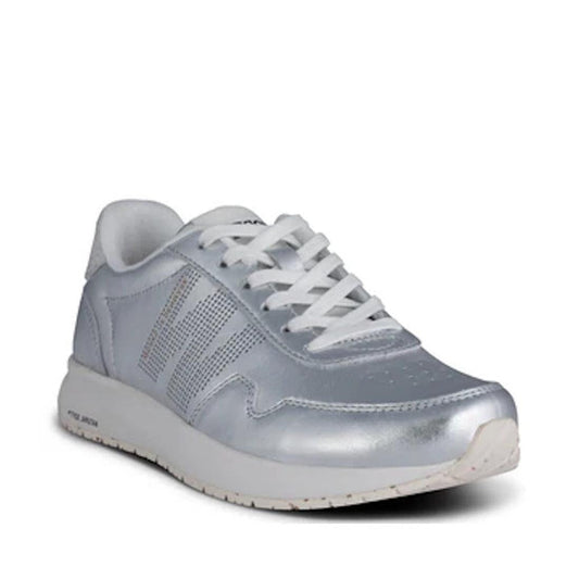 The Woden Womens Sneaker Nora Natural Soft Metallic Silver features a silver finish, white laces, a recycled rubber sole, and subtle side perforations, displayed against a plain white background.