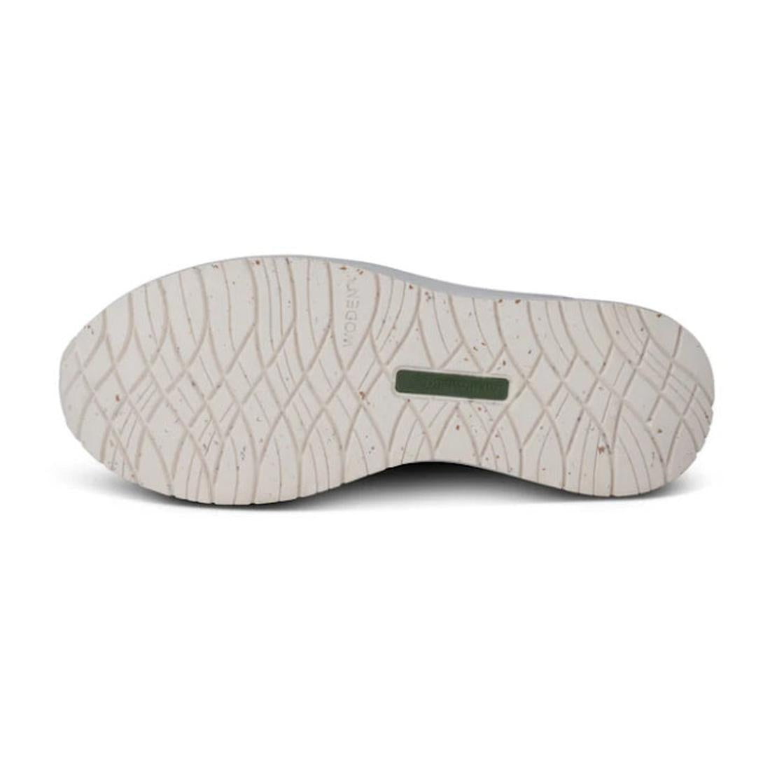 The image shows the sole of the Woden Womens Sneaker Nora Natural Soft Metallic Silver, featuring a light color, wavy textured tread, and a small rectangular green section near the arch. It's crafted with recycled rubber and appears clean and unused., 424