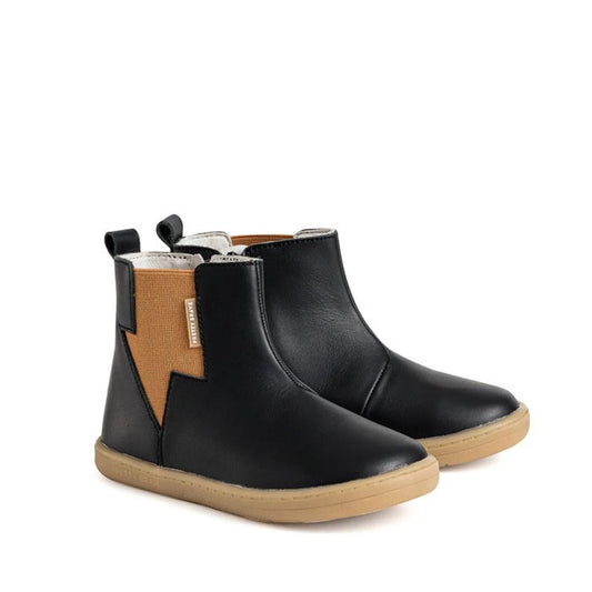 The Pretty Brave Electric Boot - Black: cozy black kids’ ankle boots with tan elastic panels, beige pull tabs, and grippy brown soles.  ksnz