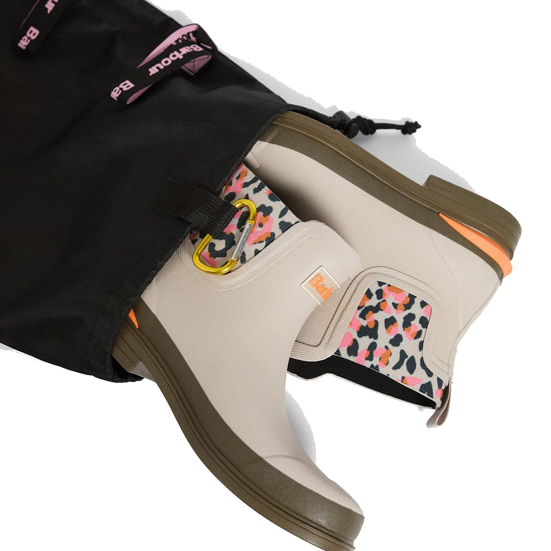 A pair of Barbour Abbeyfield Packable Ankle Wellingtons Mist, beige with olive soles and vibrant leopard print lining, shown partially out of a black drawstring bag with pink Bax branding. Lightweight and ideal for travel or outdoor adventures., 51823, 51