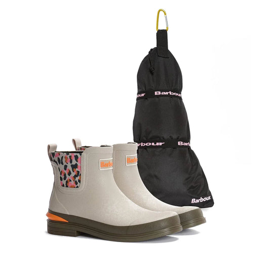 The Barbour Abbeyfield Packable Ankle Wellingtons Mist in light beige with multicolored side panels and orange accents are shown beside a black Barbour boot bag featuring pink lettering and a yellow hanging loop.