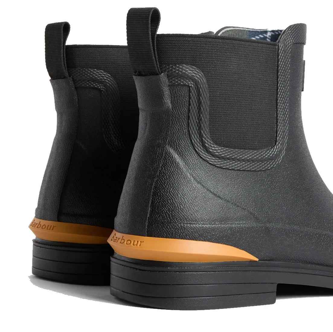Close-up of the heels of Barbour Abbeyfield Packable Ankle Wellingtons Black, featuring textured surfaces, elastic side panels, and an orange branding detail above the sole—lightweight ankle boots ideal for festivals or wet weather., 54323, 5063669380451,