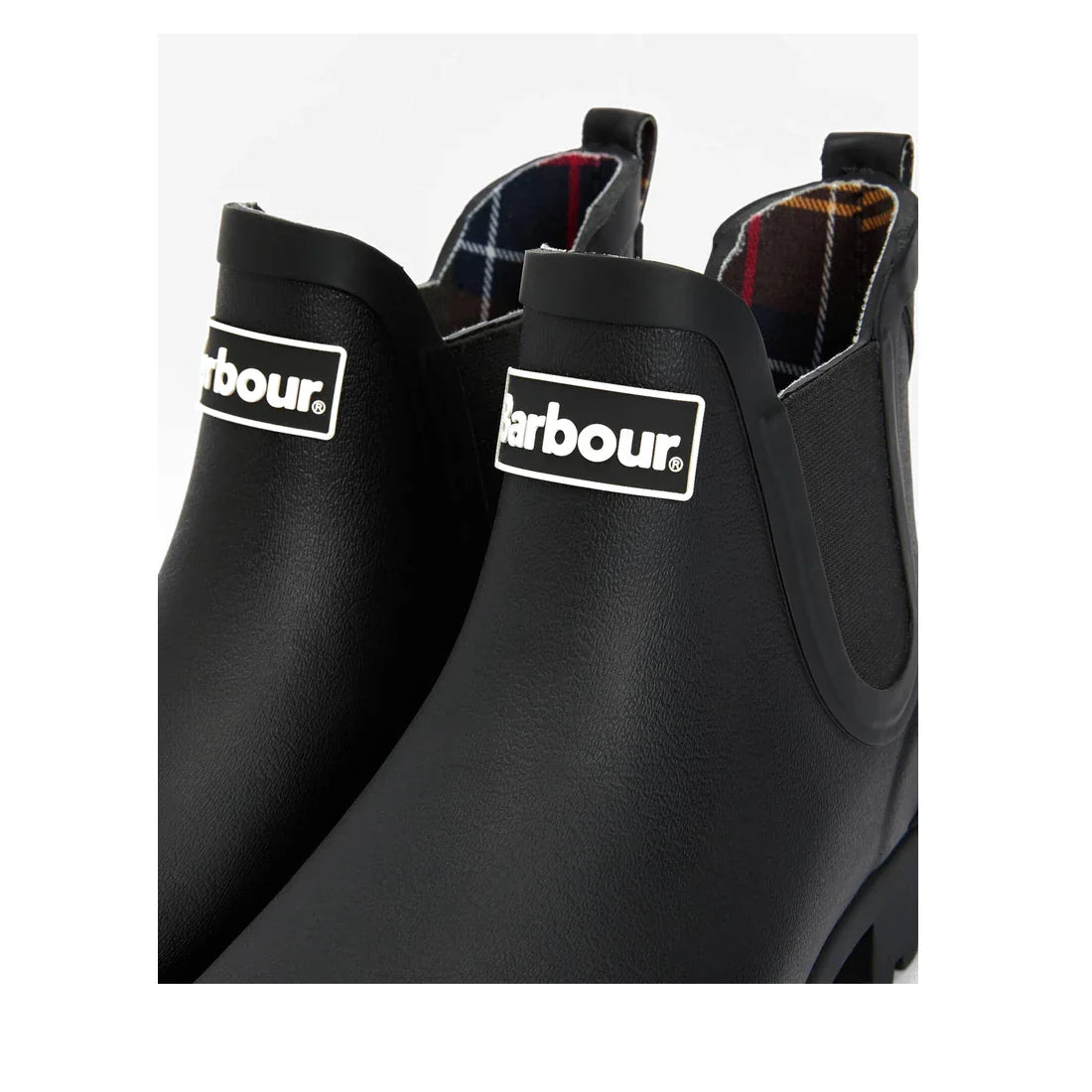 Close-up of two Barbour Wilton Black Chelsea Wellingtons Womens Rainboots with elastic side panels, front Barbour logo, and an interior tartan lining in red, blue, yellow, and white plaid for a classic touch., 190375411423, 190375411546, 190375411614, 190
