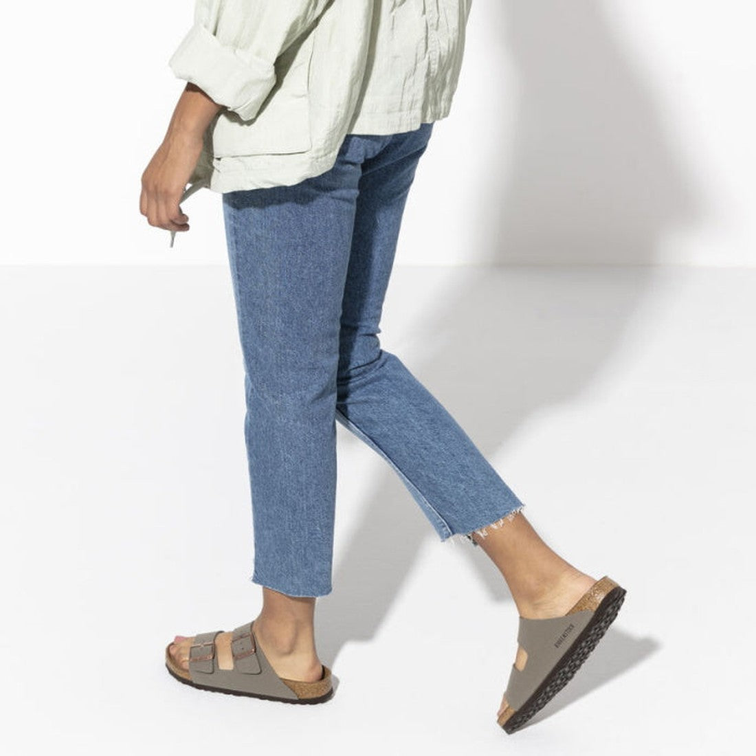 Back view of a women taking a step wearing a pair of stone birkenstock arizona sandals. 4013871744986,4013871744993,4013871745006,4013871745013,4013871745020,4013871745037,,,,,,,
, 32637, 4013871744986, 4013871744993, 4013871745006, 4013871745013, 4013871