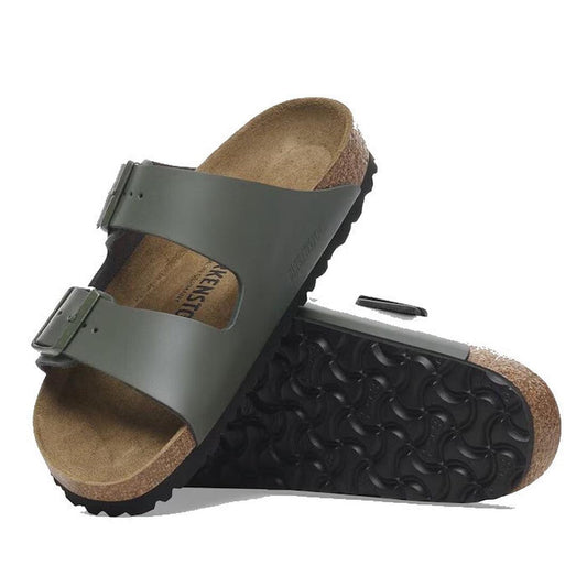 A pair of Birkenstock Arizona Smooth Leather Thyme (Regular Width) sandals with adjustable two-strap design and cork soles; one sandal stands upright while the other rests on its side, showing the sole.