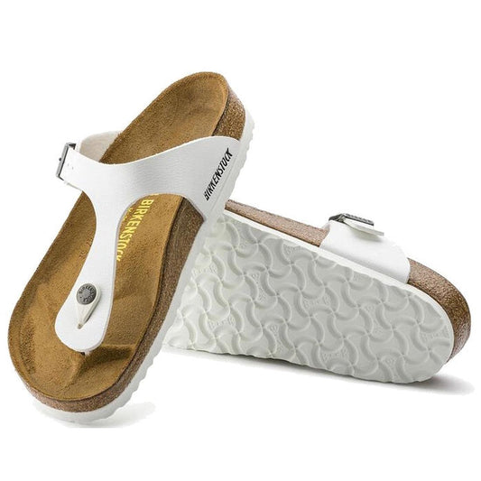 A pair of Birkenstock Gizeh Womens Birko Flor White Regular Width sandals with cork contoured footbeds and textured white soles. One sandal stands upright, the other lies on its side to display the unique sole tread pattern.
