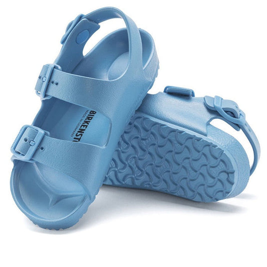 A pair of Birkenstocks Kids Sky Blue Milano EVA Sandal Narrow Width features adjustable straps and textured soles—waterproof and perfect for active little feet. One sandal stands upright, the other lays on its side.