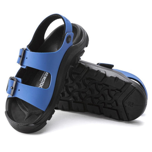 A pair of Birkenstock Mogami Narrow Kids Ultra Blue Black Birko Flor sandals feature adjustable straps, rugged black soles, and insole branding. One waterproof sandal stands upright; the other tilts to reveal its tread.