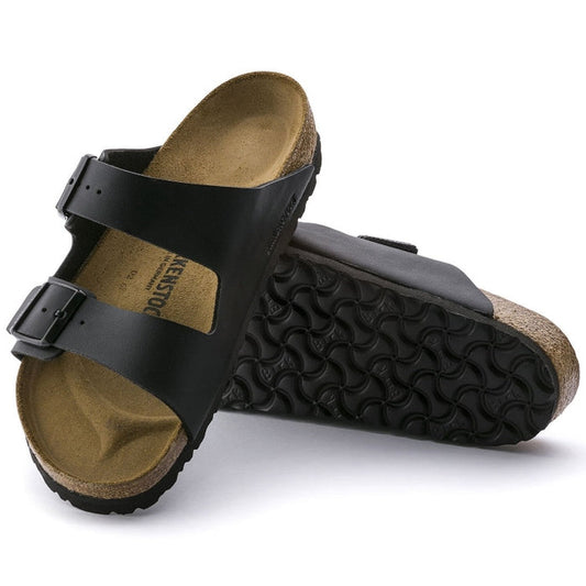 a pair of Birkenstock Arizona Birko Flor Black Regular Width with double straps, one over the foot and one over the toes with buckle adjustment. Staps are linked at the sides of the foot. Synthetic straps and a suede leather footbed, with a cork sole.,