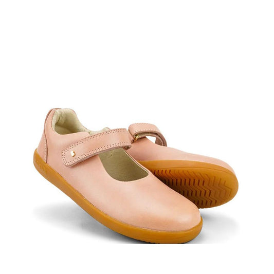The Bobux Kid+ Delight Mary Jane Dusk Pink 831625Z features pink leather, tan rubber soles, and a single hook-and-loop strap—classic girls' shoes showcased against a white background.