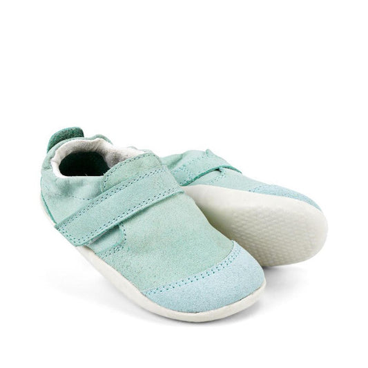 The Bobux XP Xplorer Marvel Mist Blue Dress Shoe First Walker 501227 is a pair of light blue baby shoes with velcro straps and white rubber soles, displayed against a plain white background.