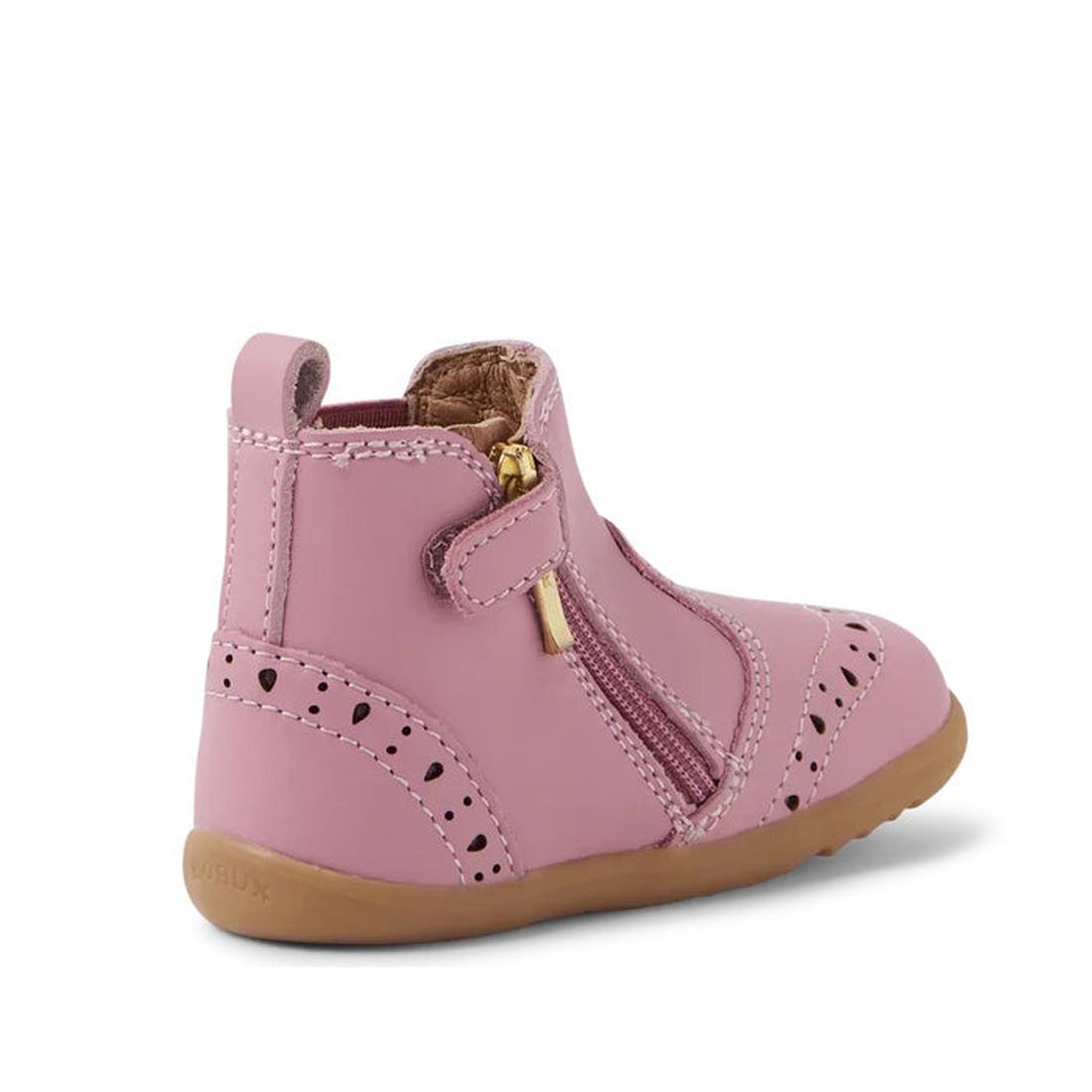 The Bobux Step Up Billie Girls Boot in Lilas Pink features decorative perforations, a brown rubber sole, and a gold side zipper. Displayed at an angle to show the side and back, it's ideal for toddlers taking their first steps., 9420068543560,
94200685435