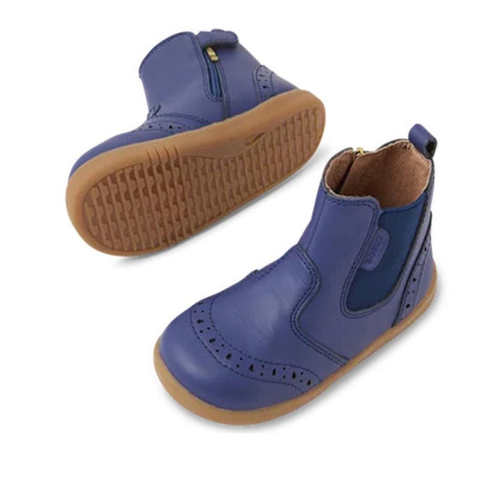 The Bobux Iwalk Billie Toddlers Leather Boot in Future Dusk Blue/Purple features brown rubber soles, side zipper closure, elastic panels, decorative perforations, and pull tabs at the back.