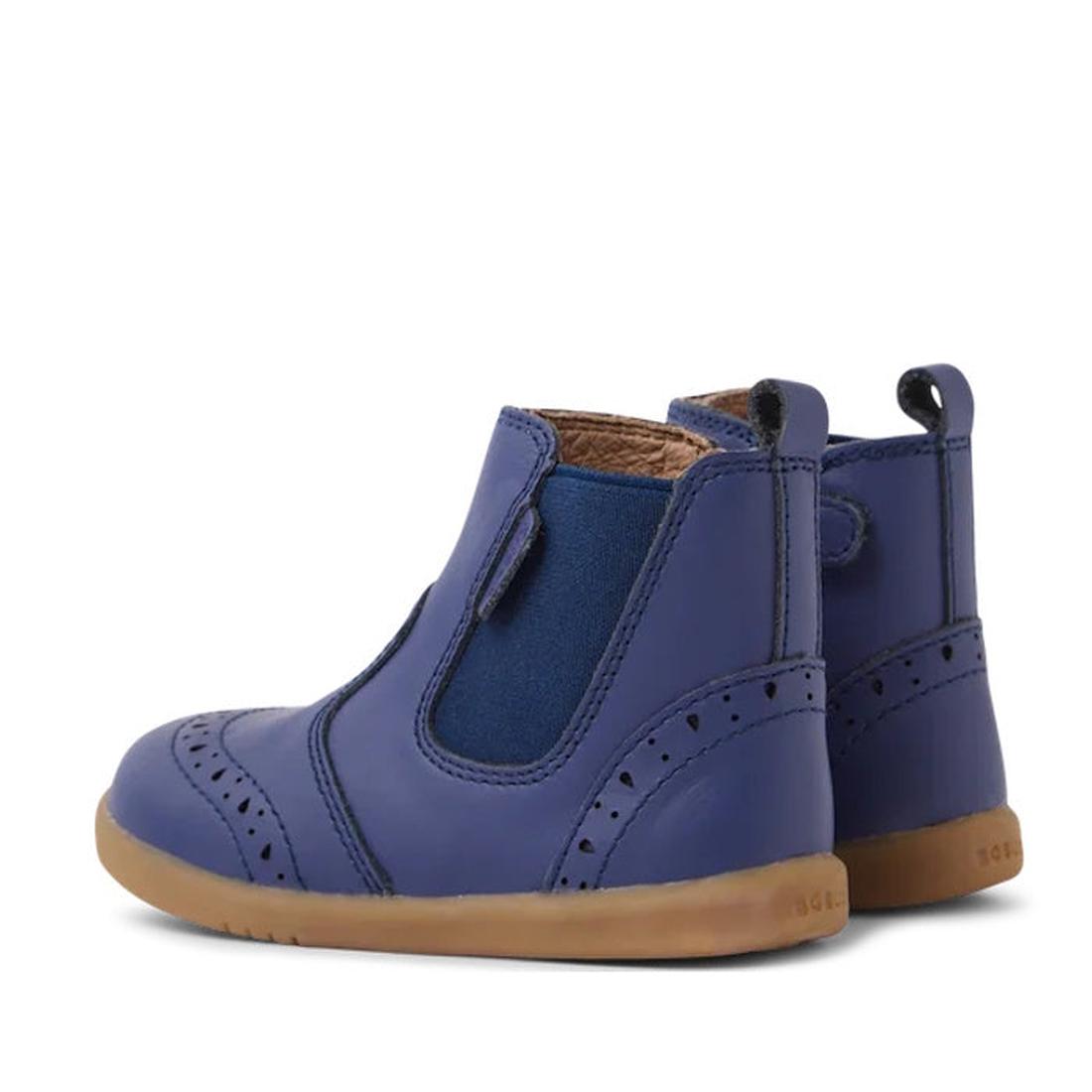 The Bobux Iwalk Billie Toddlers Leather Boot in Future Dusk Blue/Purple (652002) features elastic side panels, decorative perforations, brown rubber soles, and pull tabs at the back, shown from a rear side angle., 9420068543706,
9420068543713,
94200685437