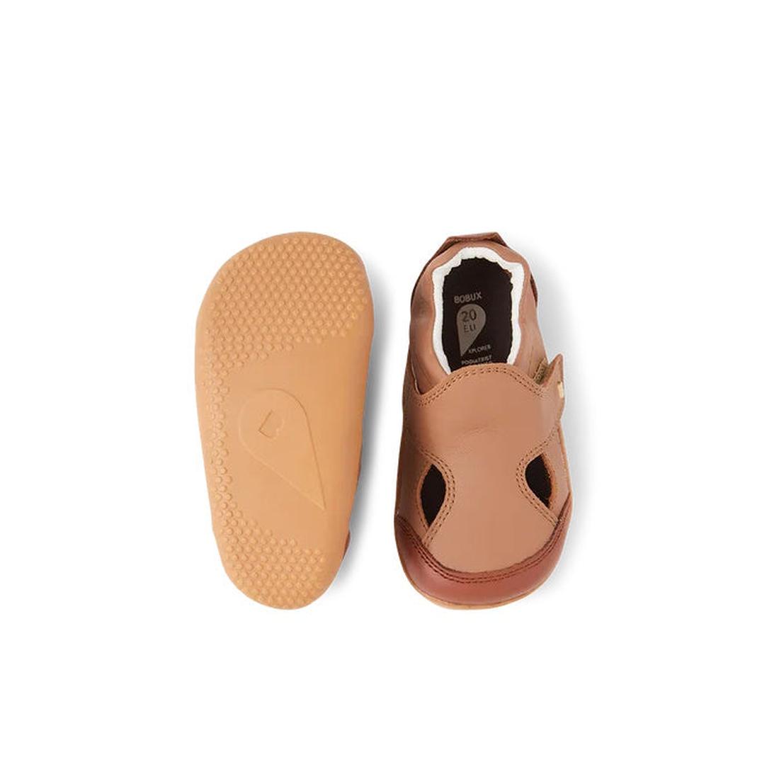 The Bobux XP Explorer Breeze First Walker Sandal Brown 502407 is shown: one upright, highlighting its open-toe design and velcro strap; the other displays a flexible, textured non-slip sole—ideal for toddlers’ first steps., 9420075761438, 9420075762749, 9