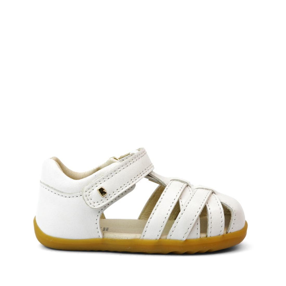 The Bobux Step Ups Cross Jump White 731106 Closed Toe Sandal features a leather upper, crisscross straps, hook-and-loop closure, and a light brown sole—ideal as a first walker. Shown on a plain white background., 9420062083901, 9420062083918, 942006208392