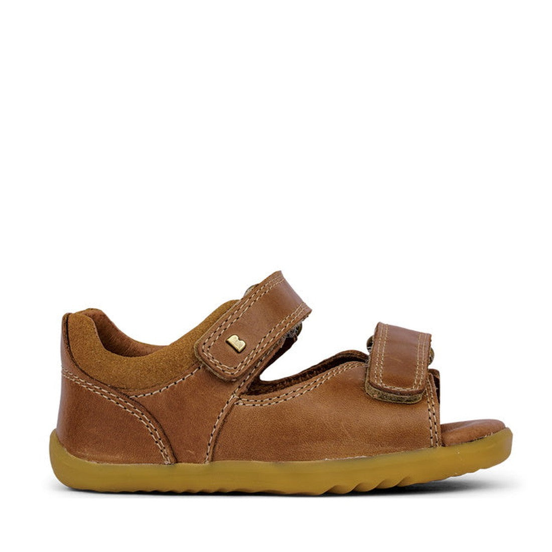 The Bobux Step Up - Driftwood 728609A Caramel Tan is a brown leather toddler sandal with a closed heel, open toe, and two adjustable Velcro straps. Its flexible light brown sole makes it perfect as a first walker. Displayed on a white background., 9420062