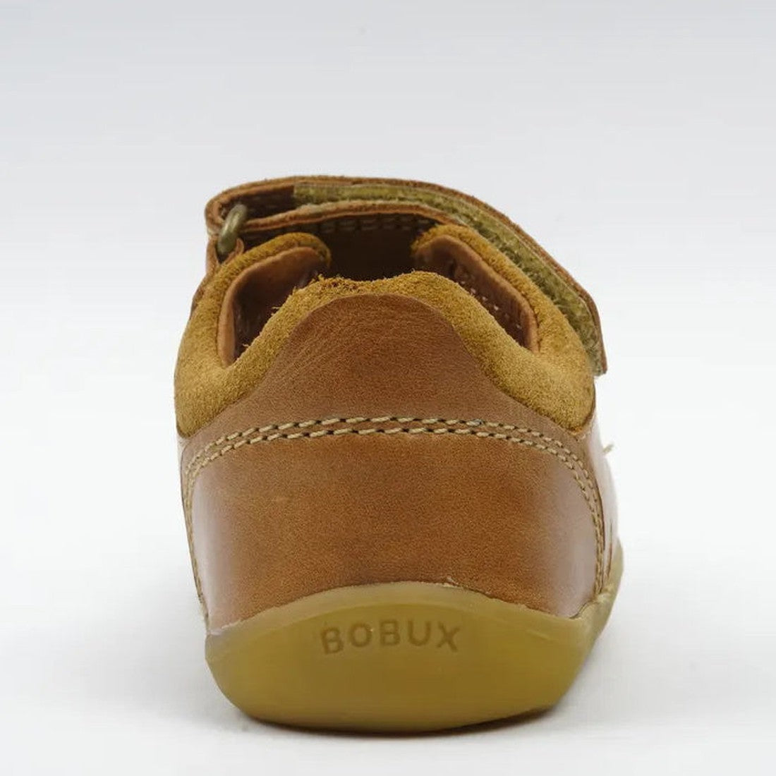The Bobux Step Up - Driftwood 728609A Caramel Tan is shown from the back, featuring a tan sole embossed with BOBUX and visible stitching. With a closed heel for support and comfort, it's perfect as toddler walking shoes., 9420062048931, 9420062048948, 942