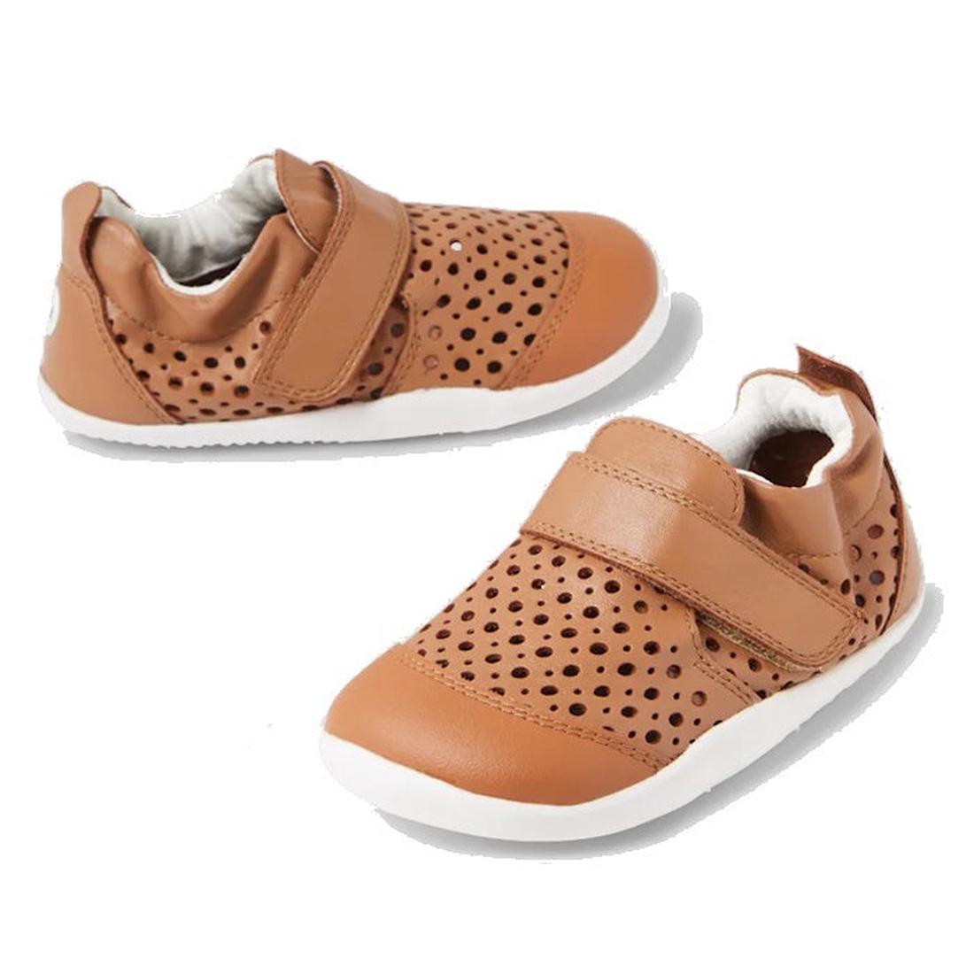 A pair of Bobux Punch first walking crawing shoes with holes over the top of the foot for breathability and a single velcro strap over the top of the foot.Eleastic at the heel and reenforced toe brown children's shoes with white soles on a white backgroun