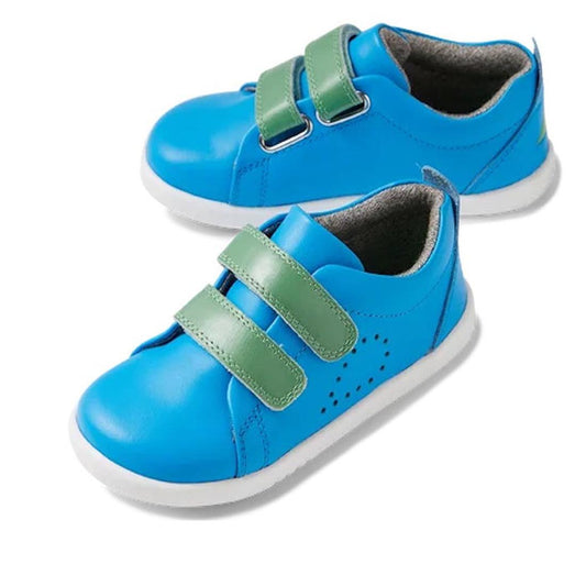 The Bobux Iwalk Grass Court Brilliant Blue Leather Trainer 640512 is a pair of blue toddler sneakers with white soles, green double Velcro straps, side perforations, and a soft gray lining for comfort.