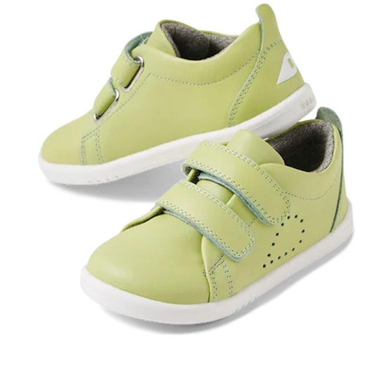 The Bobux Iwalk Grass Court Shadow Lime Leather Trainer 640517 is a pair of light green kids' shoes with white soles, Velcro straps, side perforations, and a white logo near the heel.
