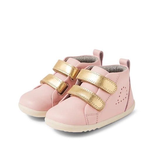 The Bobux Step Up SU Hi Court Boot Ballet Pink 750818 is a pair of pink kids' leather sneakers with white soles, two shiny gold Velcro straps per shoe, decorative side stitching, inspired by classic Grass Court High designs.