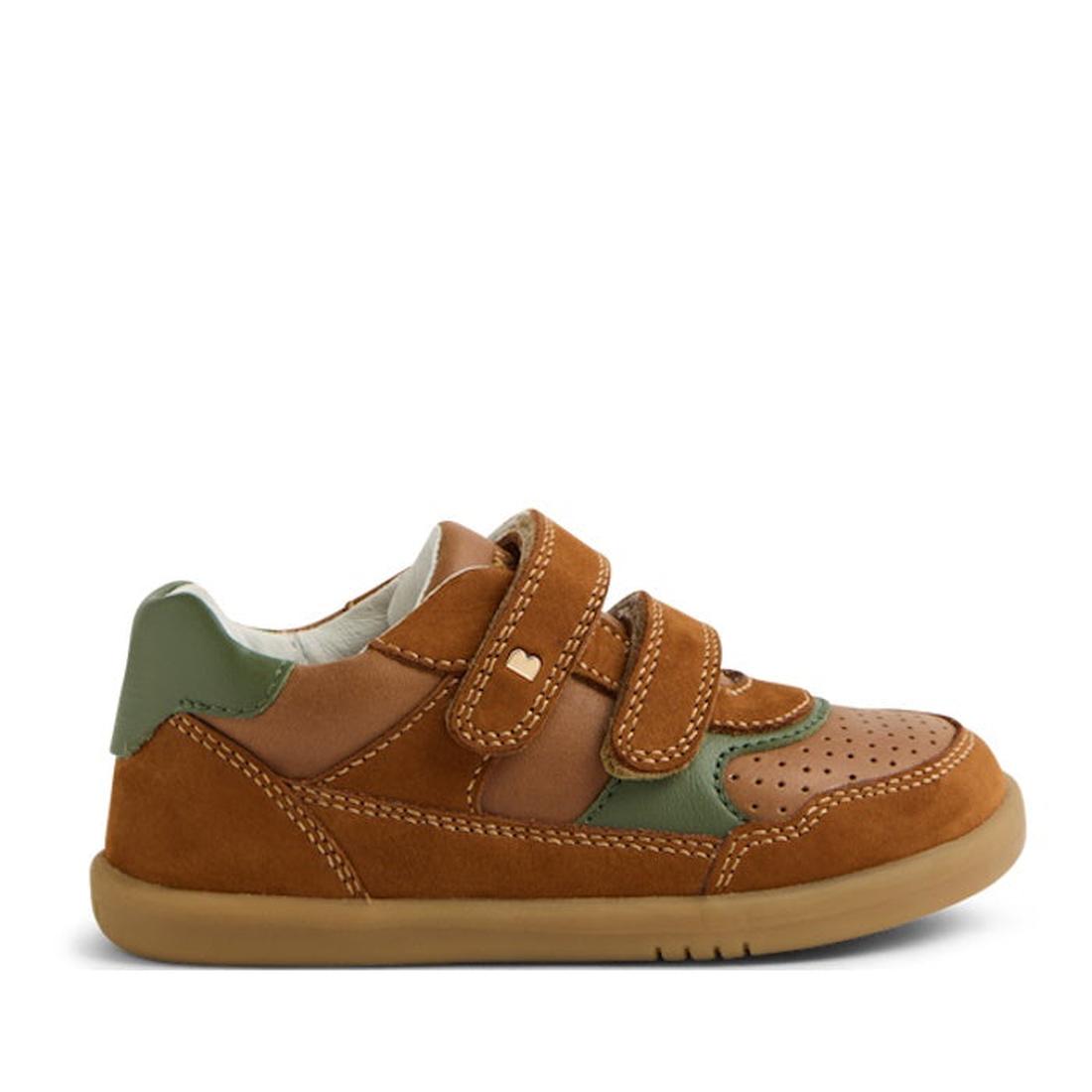 The Bobux IW Iwalk Hunter Leather Sneaker in Caramel Tan is a kids' shoe featuring brown and tan Quickdry leather, green accents, perforated toe, and two adjustable Velcro straps, shown from the side on a white background.