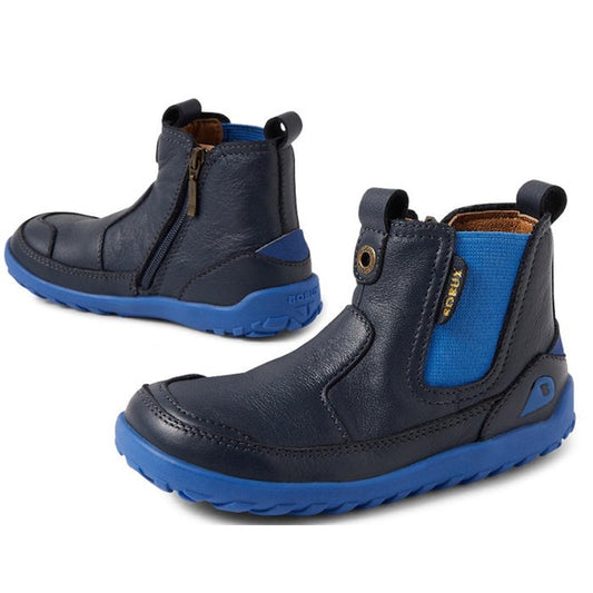 The Bobux IW Iwalk Trail Leather Boot Navy Alpha is a rugged kids' boot in navy leather with bright blue zero-drop soles, blue elastic side panels, brown pull tabs, side zippers, and a barefoot-shaped toe box for comfort.