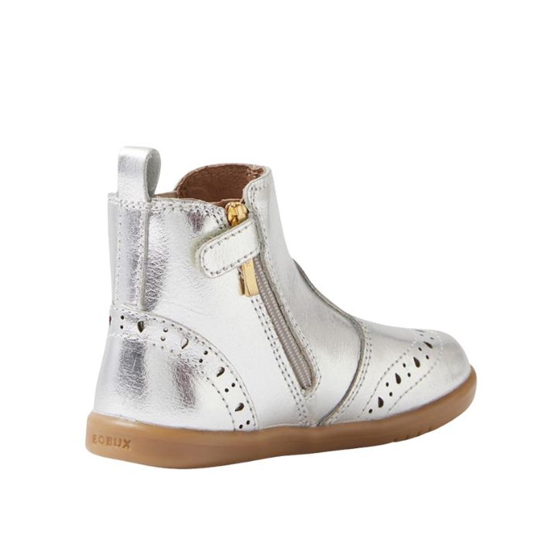 The Bobux IW Iwalk Billie Jodhpur Girls Leather Boot in silver features a shiny leather upper, tan flexible sole, side zipper, decorative perforations, and heel pull tab. This toddler boot is shown from the side., 9420074856302, 9420074856319, 94200748563