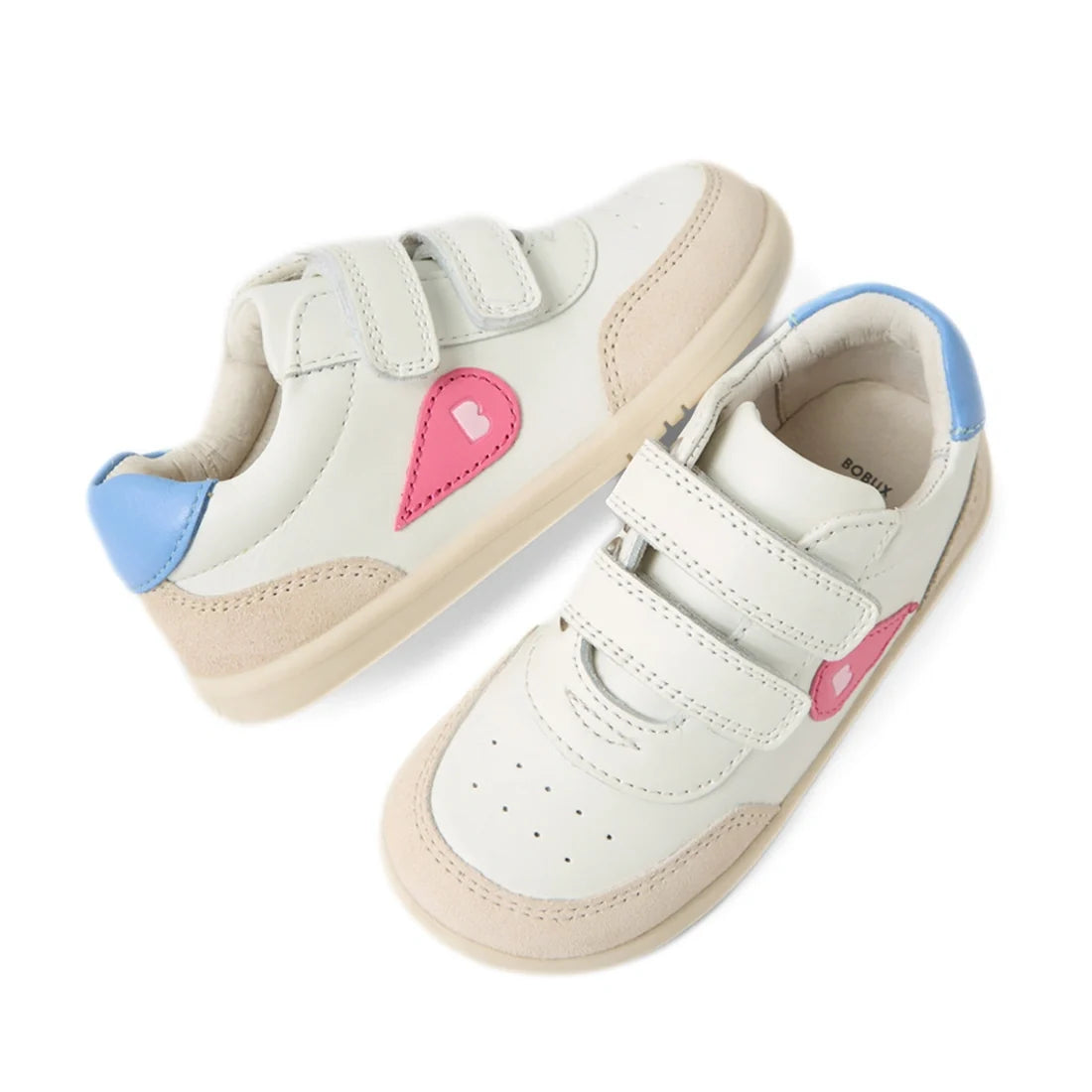 Two pairs of Bobux IW Iwalk Toddlers Champ Leather Sneakers in White Pink, featuring beige soles, beige suede accents, blue heel tabs, and pink heart-shaped designs on the sides. These kids’ leather sneakers are designed with two hook and loop straps for 