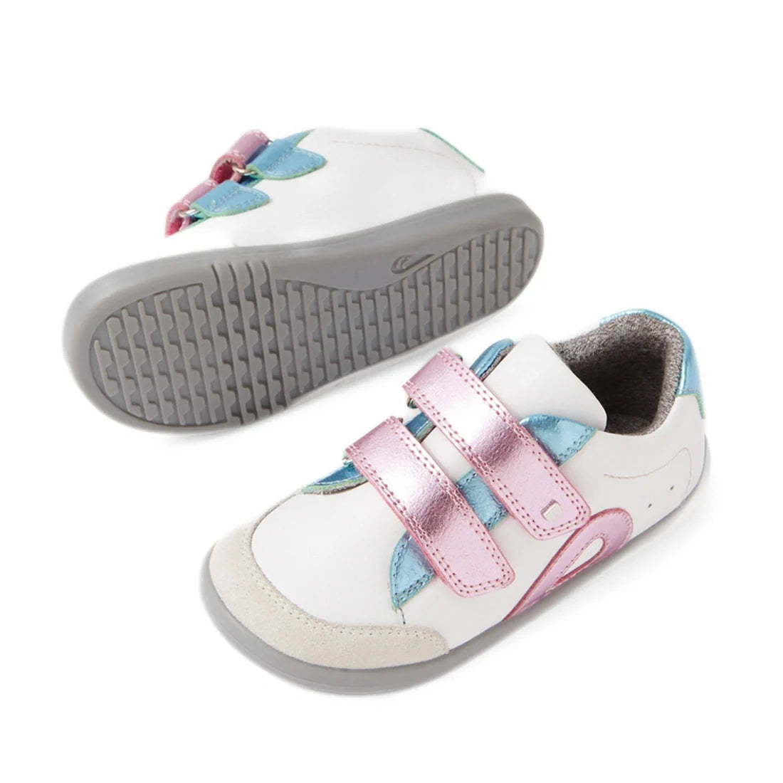 Two Bobux IW Iwalk Blaze Toddlers Leather Sneakers in white leather feature gray soles, pink metallic Velcro straps, and blue metallic accents. One shoe stands upright while the other rests on its side to display the sole—ideal as an everyday sneaker for 