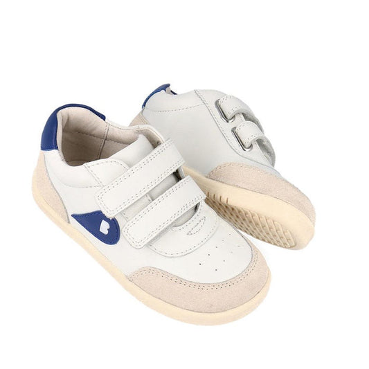 The Bobux Kids IWalk IW Champ Sneaker Chalk White Blue 650501 is a pair of unisex kids' sneakers in white with beige soles, blue accents, and two Velcro straps, shown on a white background.