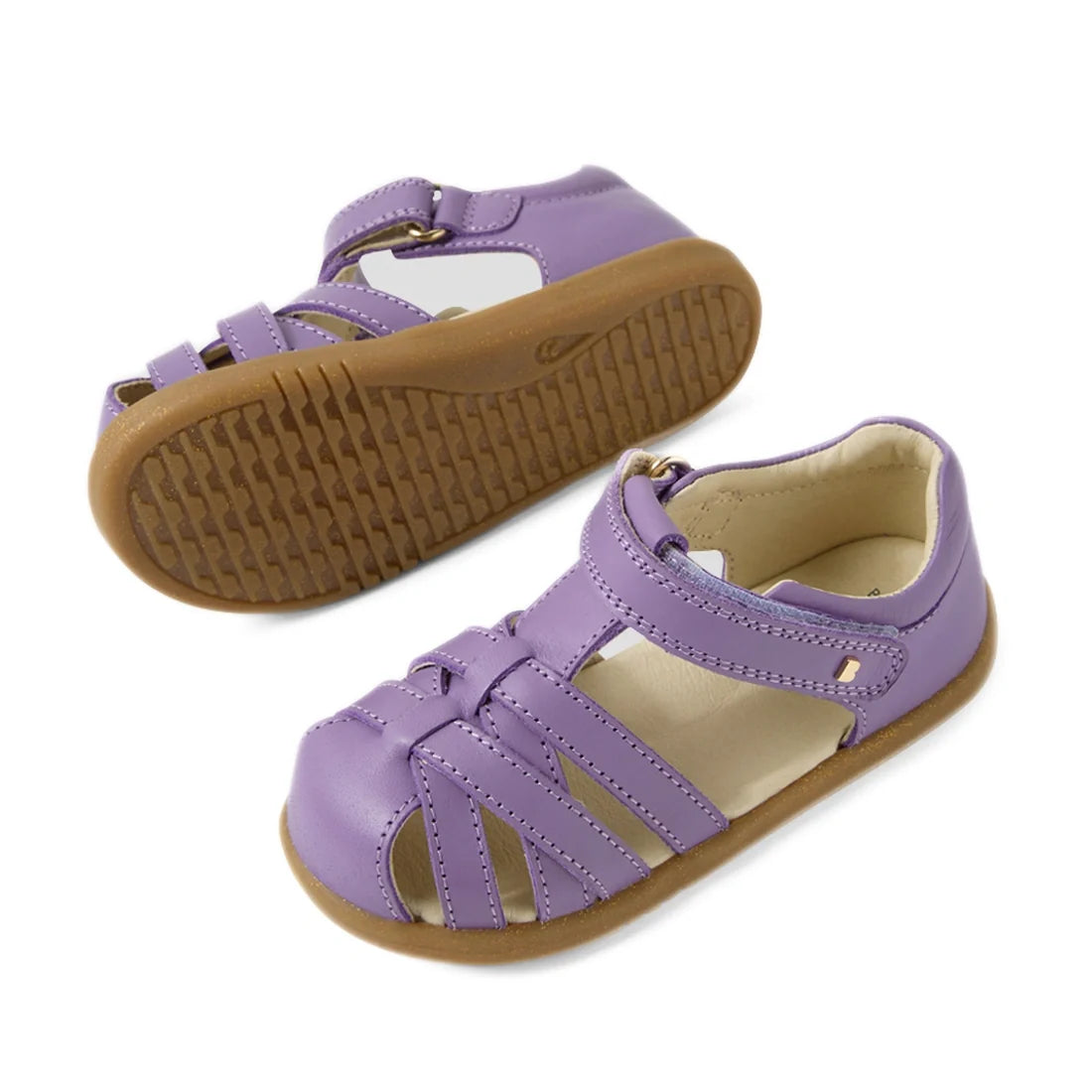 A pair of Bobux Iwalk IW Cross Jump Toddlers Purple Haze leather sandals with closed toes, tan rubber soles, and adjustable straps. One sandal is upright, while the other displays the sole., 9420074808714, 9420074808721, 9420074808738, 9420074808745, 9420