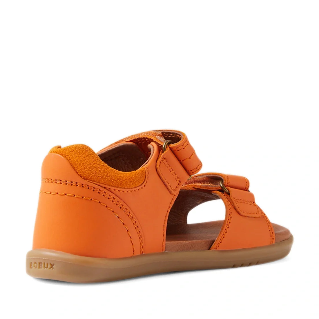 The Bobux IWalk Driftwood Sandal in Orange Peel is an open-toed leather sandal for toddler boys, featuring a closed heel, adjustable straps, and a tan rubber sole. Inspired by the classic Driftwood style, this sandal is shown from a rear side angle on a p