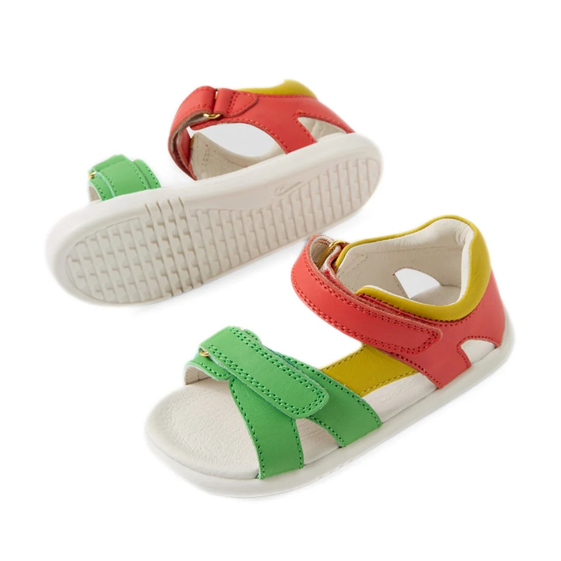 Two adventure-ready Bobux IWalk Dune Toddlers Sandals in Grenadine Red, designed with white soles, green and red adjustable straps, yellow accents, soft leather uppers, Velcro closures, and open toes. Displayed on a plain white background., 9420074855091,