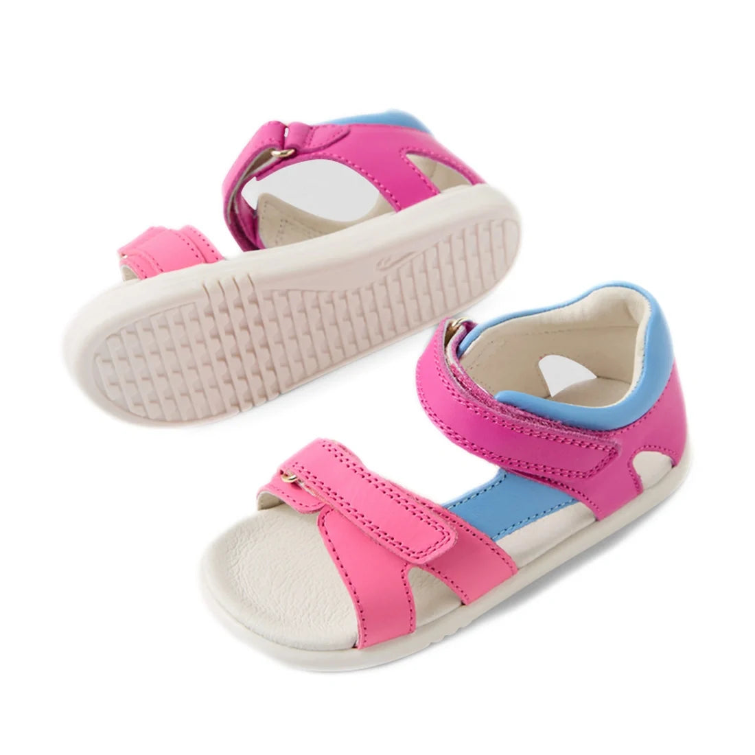 Two rose violet and bright pink open-toe children’s sandals with white soles are displayed on a white background. One sandal lies on its side to reveal the sole, while the other stands upright—these are stylish and comfortable Bobux IWalk Dune Toddlers Sa