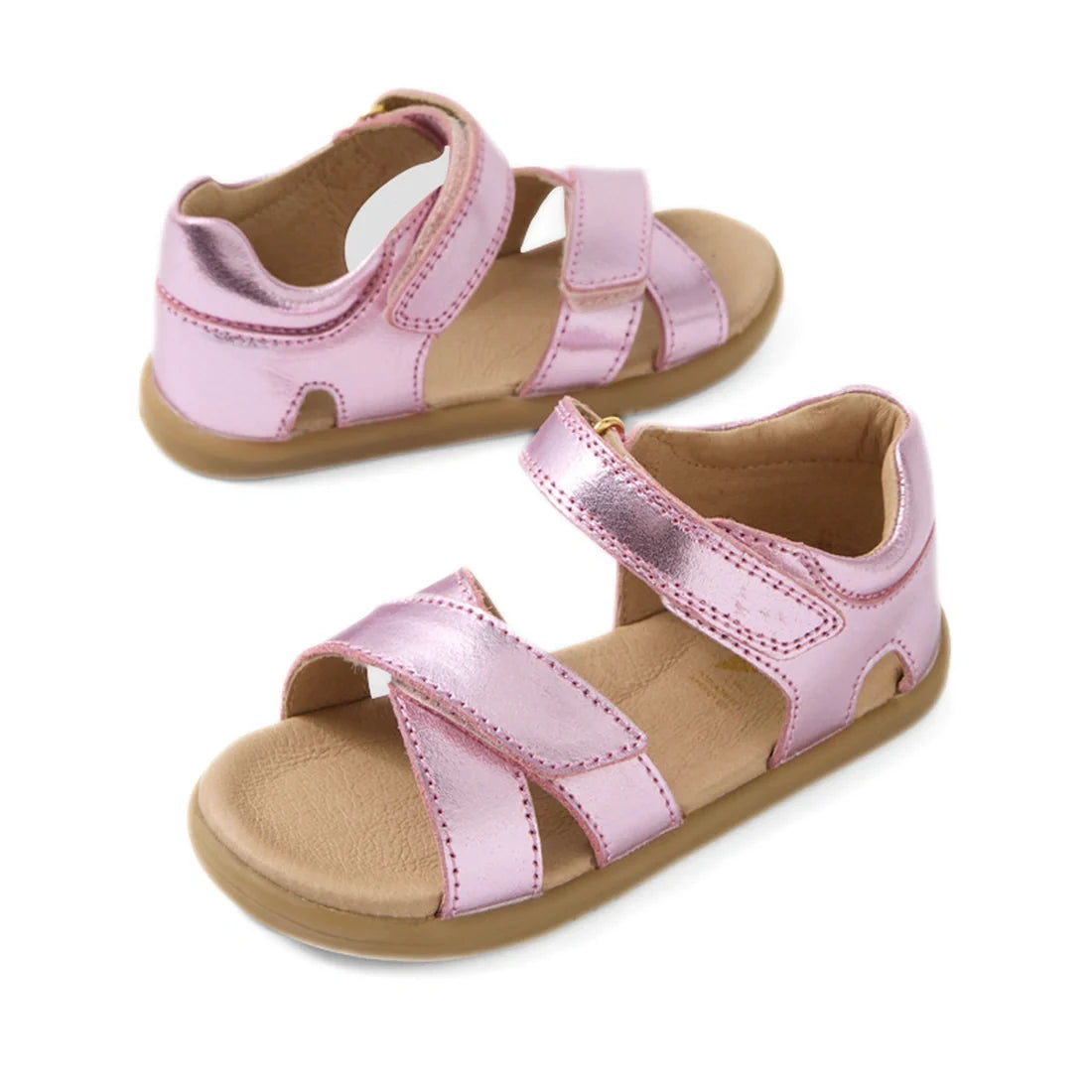 The Bobux IWalk Flora Toddlers Sandal in Pink Lemonade is a pair of metallic pink children’s sandals with crisscross straps, open toes, ankle support, and secure velcro closures. Made from breathable leather with tan soles and a cushioned insole, these sa