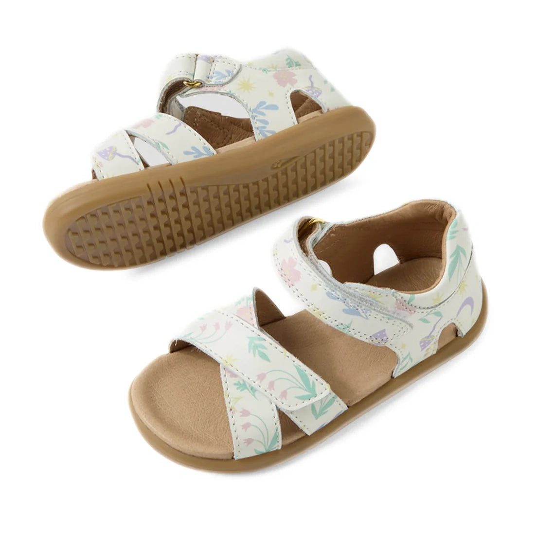 Two white Bobux IWalk Flora Toddlers Sandals featuring a pastel animal and floral pattern, tan soles, open toes, and adjustable Velcro ankle straps. One sandal is shown from the top view while the other displays the bottom sole. These leather toddler sand