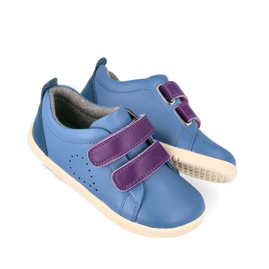 The Bobux Iwalk Grass Court Elemental Blue Leather Trainer 640505 is a unisex kids' shoe in blue with purple double Velcro straps and beige rubber soles, crafted from premium leather and shown on a white background.