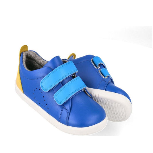 The Bobux Iwalk Grass Court Azzure Blue Leather Trainer 640507 is a unisex kids’ running shoe with velcro straps, premium blue leather upper, white soles, and yellow heel accents, shown on a white background.