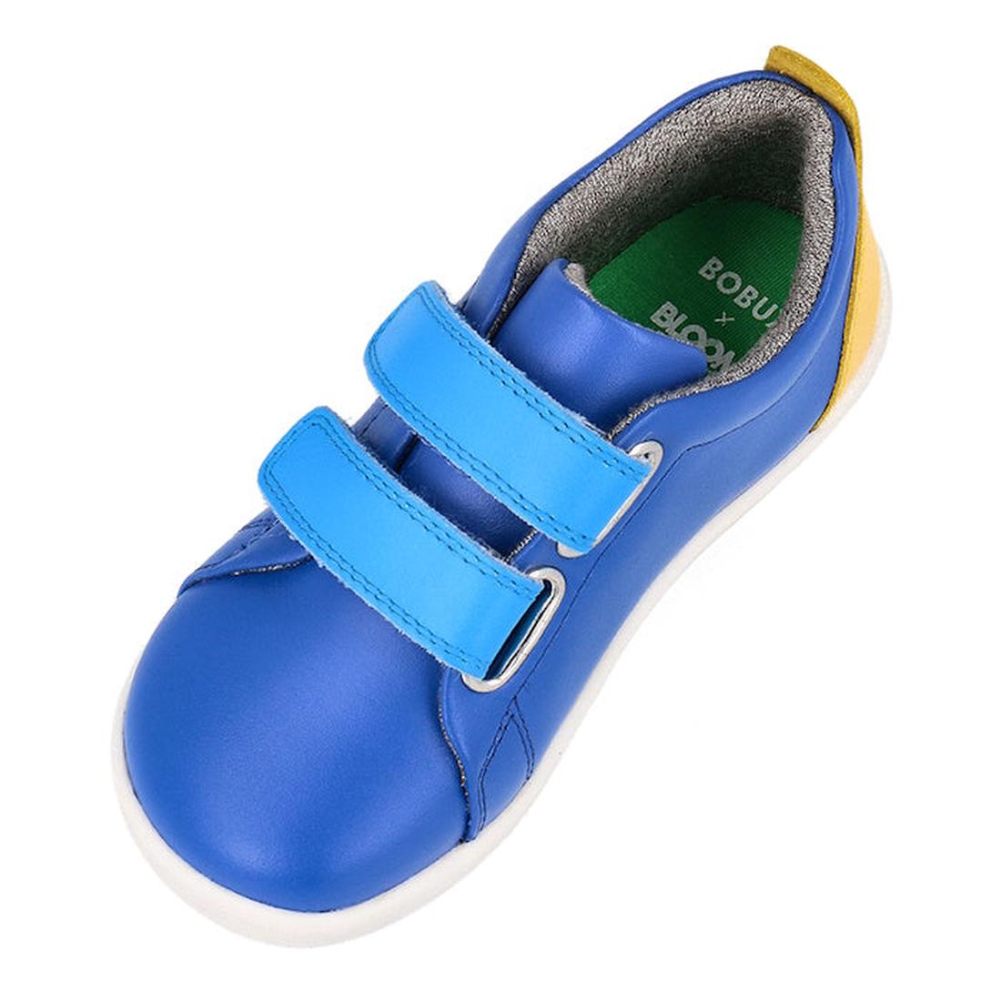 The Bobux Iwalk Grass Court Azzure Blue Leather Trainer 640507 is a unisex kids’ sneaker with two hook-and-loop straps, white sole, yellow heel pull tab, premium blue leather upper, and a green insole with white printed text., 9420075777385, 9420075769588