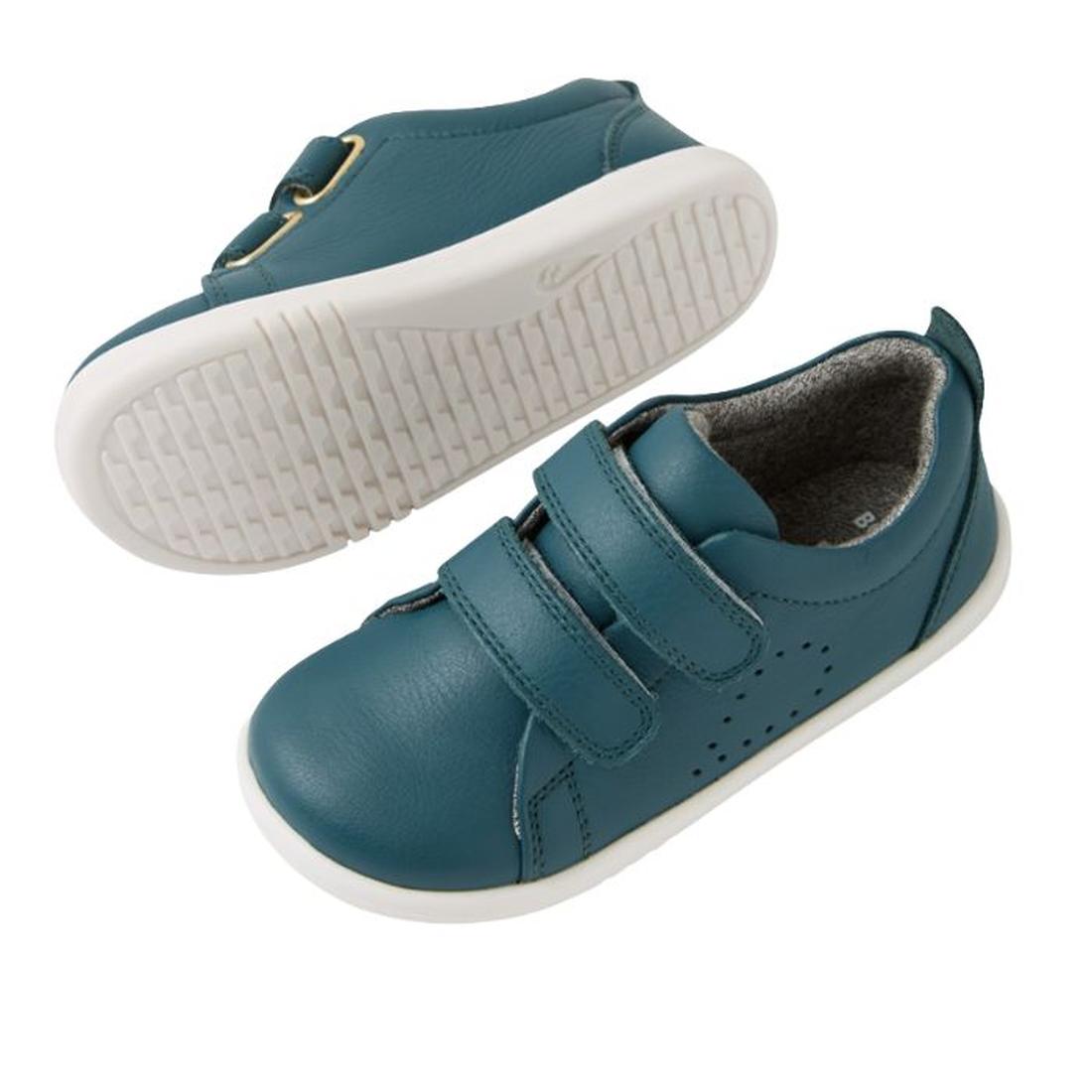 The Bobux IW Iwalk Grass Court Leather Sneaker in Mediterranean Green for toddlers features a premium leather upper, perforated sides, white soles, and two Velcro straps. One shoe is upright; the other displays its sole., 9420074806734, 9420074806741, 942